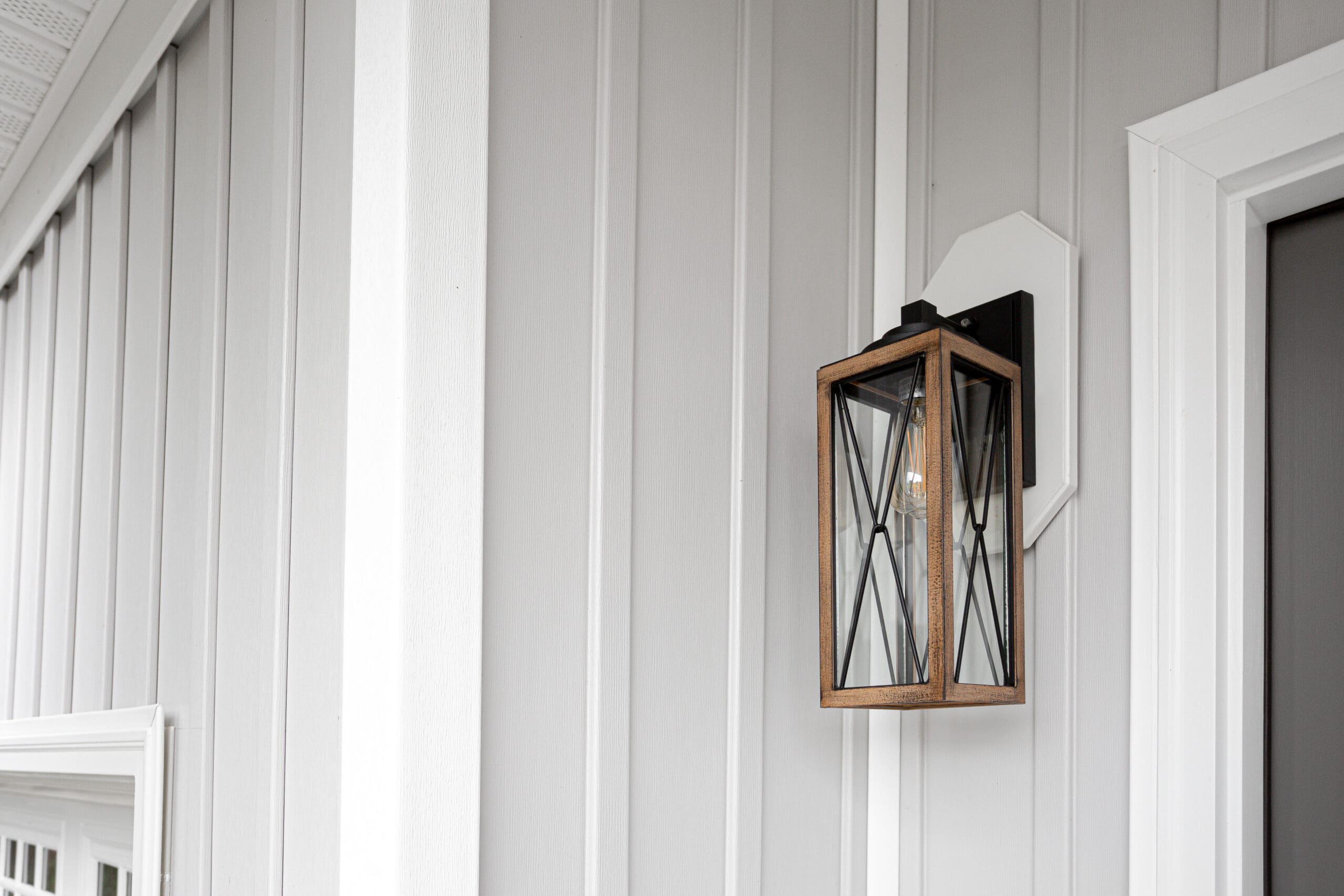 Southern Rustic Farmhouse Front Porch Light Sconce Next To Front Door and Grey Siding. Copyspace